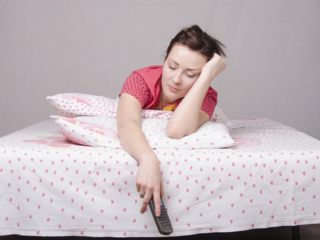 A young girl is Watching TV in bedの写真素材