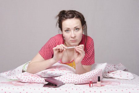 A young girl lying in bed and saws, nails nail filesの写真素材