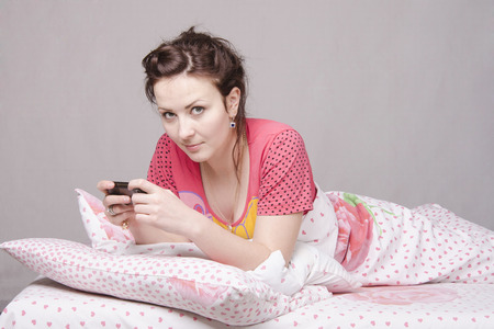 The girl lying in bed and talking on the phoneの写真素材