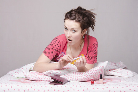 A young girl lying in bed and saws, nails nail filesの写真素材