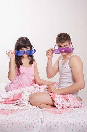 Young couple sitting in bed and each wore big glassesの写真素材