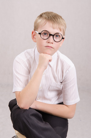 Twelve year old boy with glasses sitting on a chairの写真素材