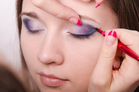 Makeup artist draws arrows beautiful young girl in the makeupの写真素材
