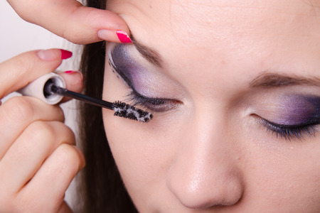 Makeup artist paints eyelashes of a beautiful young girl in the makeupの写真素材