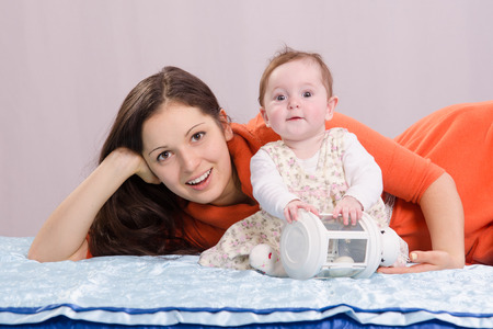 Mom and six-month daughter happily lie on the couchの写真素材