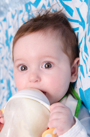 Six month old baby drinking milk from a bottle with the teatの写真素材