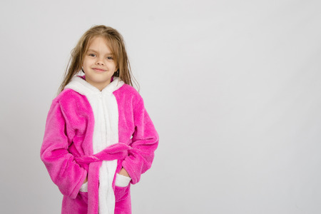 Six year old girl with wet hair in a bathrobe on a light backgroundの写真素材