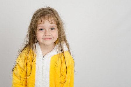 Four-year girl with wet hair in a bathrobe on a light backgroundの写真素材