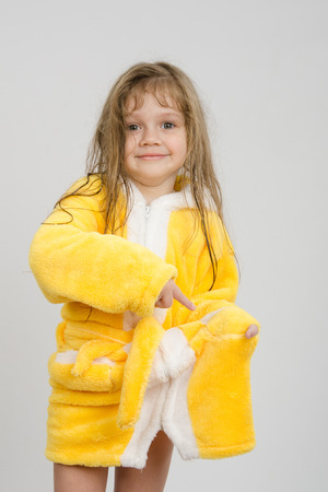 Four-year girl with wet hair in a bathrobe on a light backgroundの写真素材