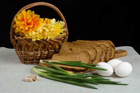 Still life on a black background.Sliced bread, onions, garlic, eggsの写真素材