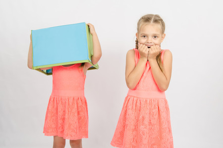 Two girls wearing a box on his head, isolated on a light backgroundの写真素材