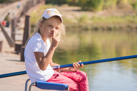 Six year old girl fishing from a bridge on a clear sunny dayの写真素材