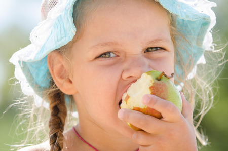 Portrait of a happy little girl in panama Europeans who eagerly bites pearの写真素材