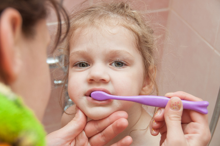 Mom helps his three-year daughter brushing teethの写真素材