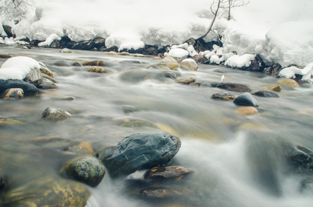 Rapidly flowing winter mountain river, blurred by a slow shutter speedの写真素材