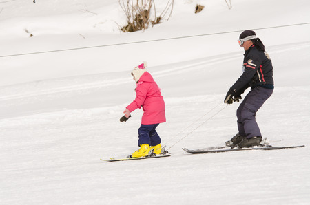 Dombay, Russia - February 7, 2015: A man learns to ski teenage girl on a snow-covered slope ski resort Dombaiのeditorial素材