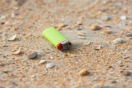 Old used lighter in the sand on the beachの写真素材