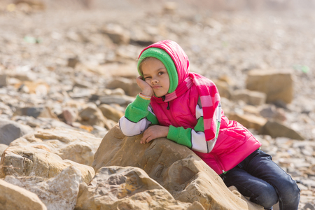 Girl bored at the seaside in the offseason lay down on a big rockの写真素材