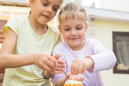 Two girls sprinkle confectionery on Easter cupcakesの写真素材
