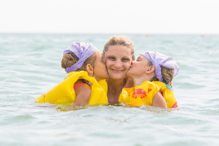 Daughters kiss mom swimming in the sea