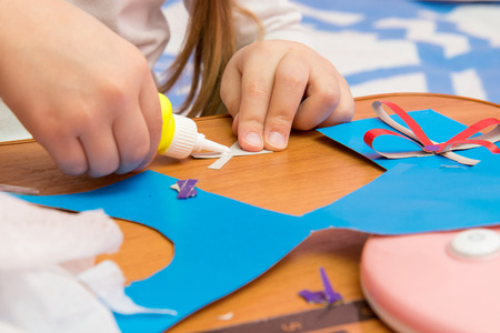 Girl sticks two strips, making crafts out of colored paperの写真素材