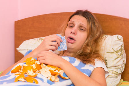 Young girl coughing heavily lying in bedの写真素材