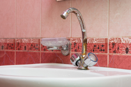 Wash basin mounted with a rusty craneの写真素材