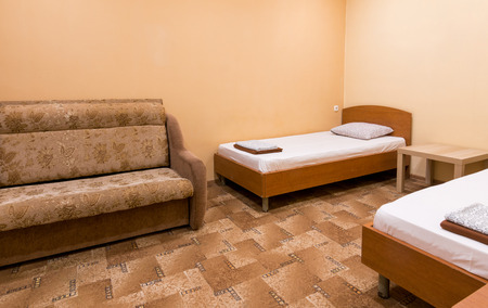 The interior of a small room with a sofa and two bedsの写真素材
