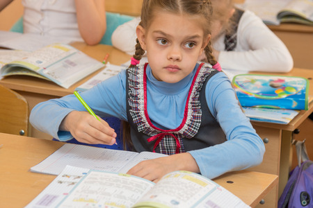 First-grader at a lesson of mathematics solves examples and look at the board
