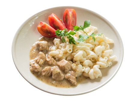 Pork goulash with macaroni and sliced tomato, isolated on white backgroundの写真素材