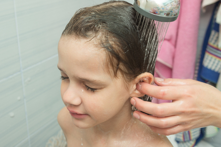 Mom washes the baby's ear under the showerの写真素材