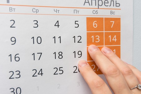 Fingers point to the weekend in the wall calendarの写真素材