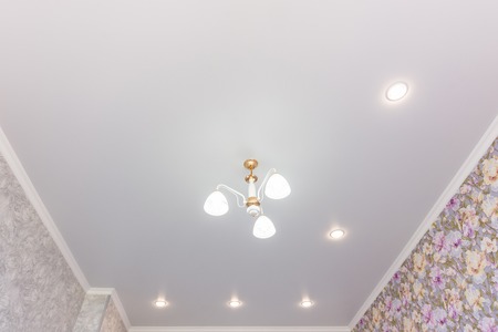 Stretch ceiling in the room with a chandelier and spotlights