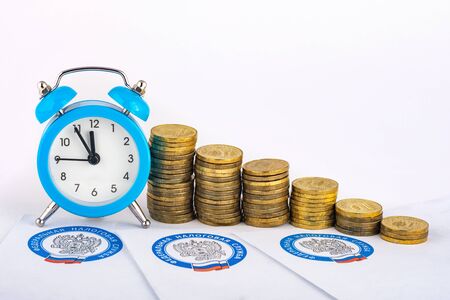 Anapa, Russia - September 3, 2019: Tax notifications, clocks and rising stacks of coinsのeditorial素材