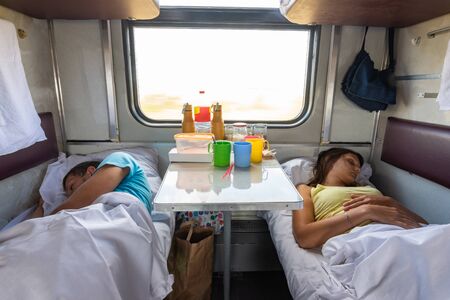 Man and woman sleep on lower shelves in a train carの写真素材