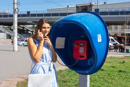 Young pretty girl talking on a payphone on a city streetの写真素材