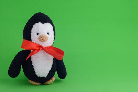 Knitted toy penguin on a green backgroundの写真素材