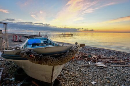 An old boat on the beach against the backdrop of a beautiful sea sunsetの写真素材
