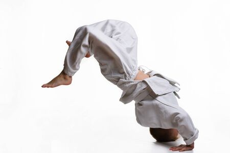 Judo boy in white kimono doing somersaultの写真素材