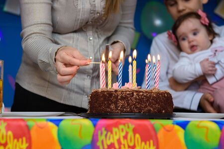 Mom lights candles on a cake at a birthday partyの写真素材