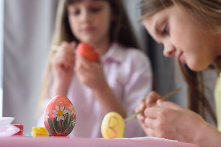Children paint Easter eggs, focus on the egg in front of themの写真素材