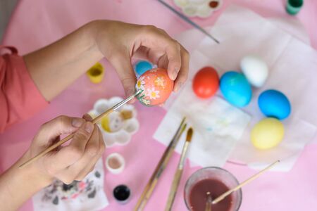 Hand paints eggs for Easter holiday.