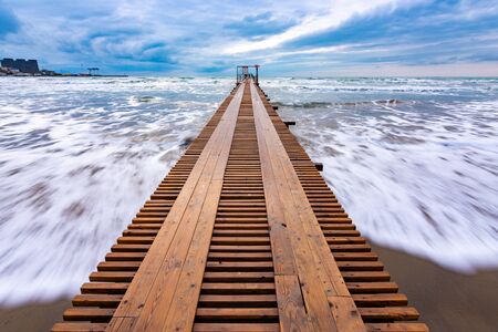 Sea surf after sunset, a wooden pier goes into the distanceの写真素材