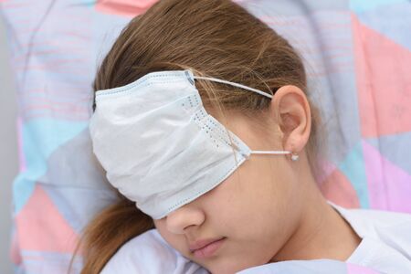 The girl fell asleep in bed, on her face and eyes she pulled on a medical mask, close-upの写真素材