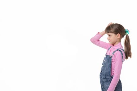 The girl puzzled scratches her head and looks at an empty spot in the frame.の写真素材