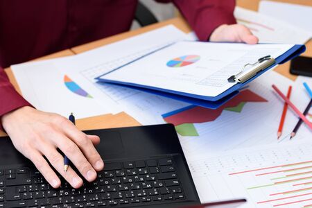 close-up of desktop with documents, laptop, graphs, tables