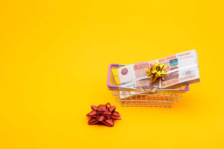 In the grocery basket is a bundle of five thousandth bills, next to it is a red bow