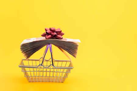 On the handles of the grocery cart lies a bundle of notes packed with gift ribbon and a red bowの写真素材