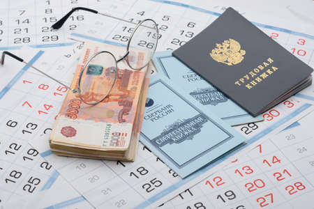 Anapa, Russia - 06/29/2020: On the background of the calendars lie a work book, a savings book, a...