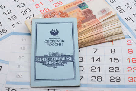Anapa, Russia - 06/29/2020: On a bundle of five-thousandth Russian banknotes lies a savings book, a background of calendar sheetsのeditorial素材
